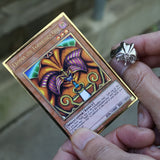 A close-up of a person holding a Yu-Gi-Oh! trading card, Exodia: The Coordinates One, with a silver ring on their finger, set against a blurred outdoor background.